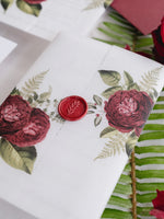 Invitación con manga de pergamino de caligrafía moderna con detalles florales de color rojo intenso y sello de cera de Burdeos