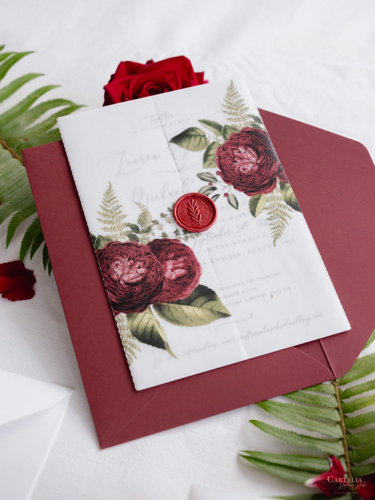 Invitación con manga de pergamino de caligrafía moderna con detalles florales de color rojo intenso y sello de cera de Burdeos