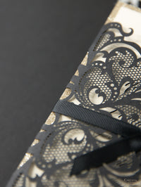 Elegante portada láser Black Opulence con diseño de lazo y purpurina dorada.