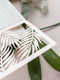 Colección de invitaciones de destino tropical cortadas con láser con hojas de palmera por la noche